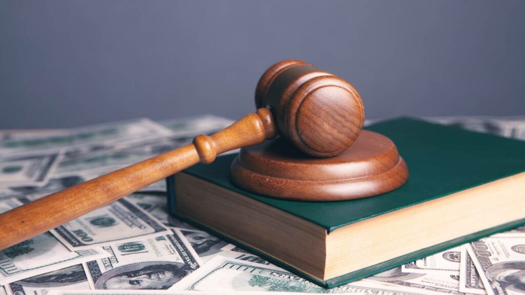 A gavel on a book of law and a stack of money bills