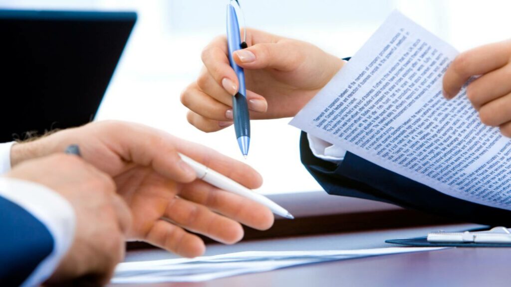 A closeup photo of two pairs of hands holding pens and papers