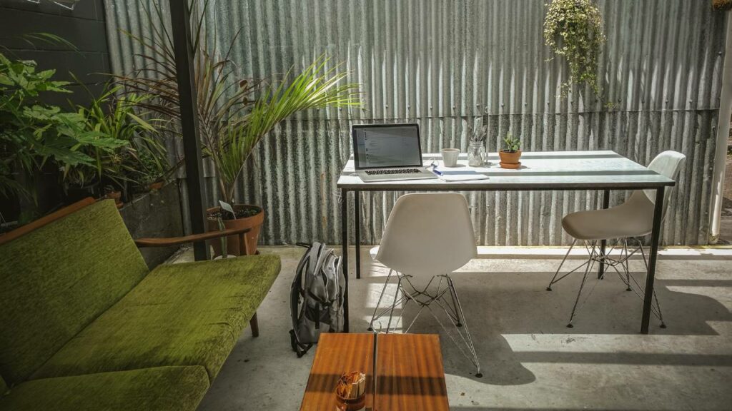 An outdoor workspace with plants and a laptop on a table